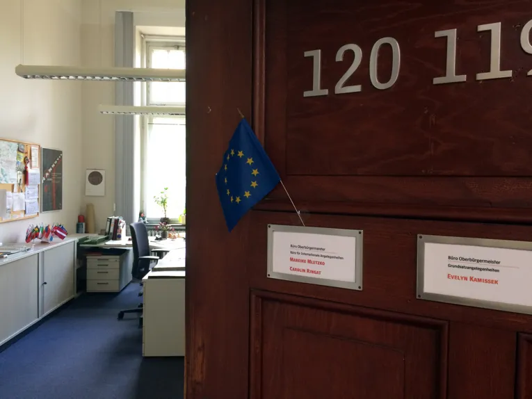 Eine halb offene Bürotür mit einer kleinen Europaflagge am Türschild.