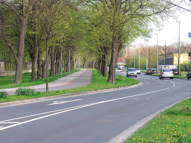 Autos fahren auf einer erneuerten Fahrbahn. Daneben ein sanierter Fahrrad- und Fußgängerweg.