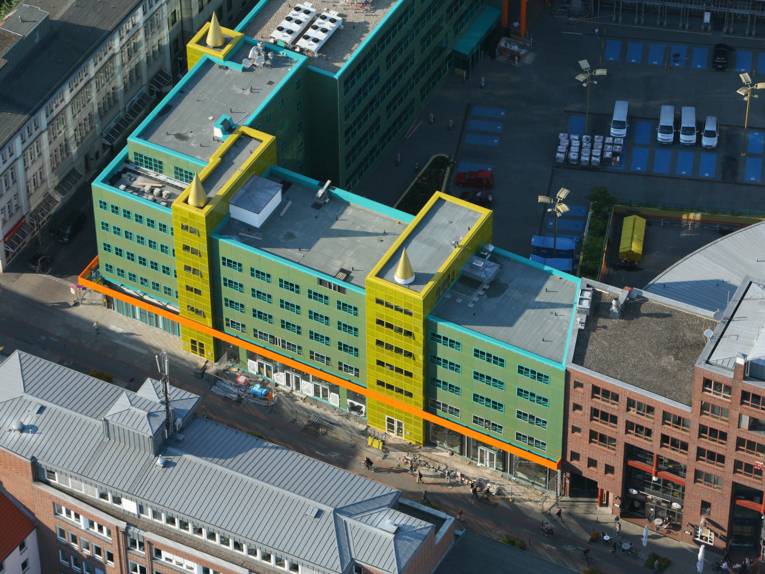 Umgebautes Büro- und Geschäftshaus mit farbiger Fassade und drei vergoldeten Spitzen auf dem Dach