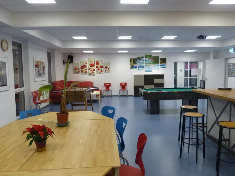 Innenaufnahme vom Jugendzentrum Vinnhorst: Eine Sitzecke, Tisch und Tresen und ein Billiardtisch