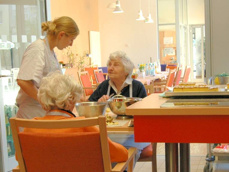 Seniorinnen und eine Helferin beim Kartoffelschälen