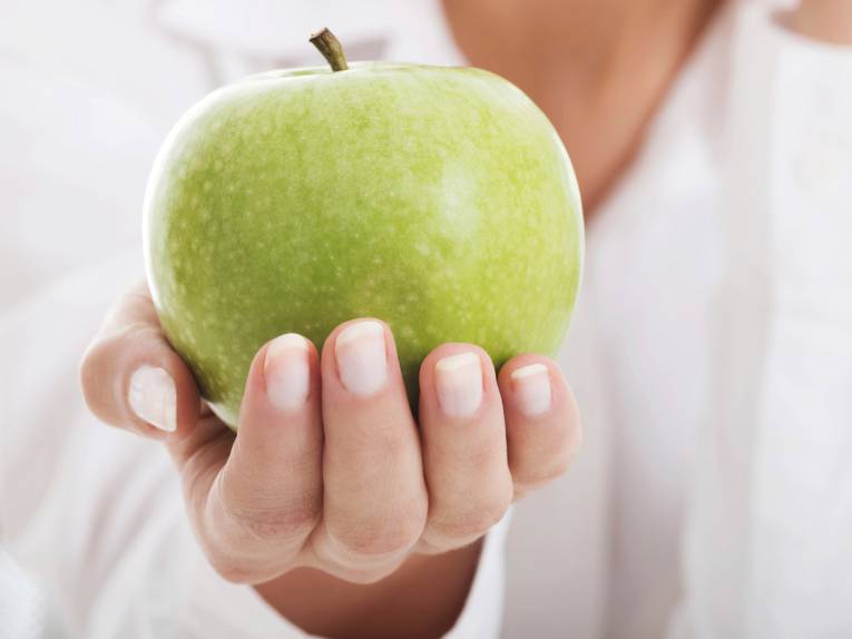 Ein grüner Apfel wird von einer Hand umschlossen