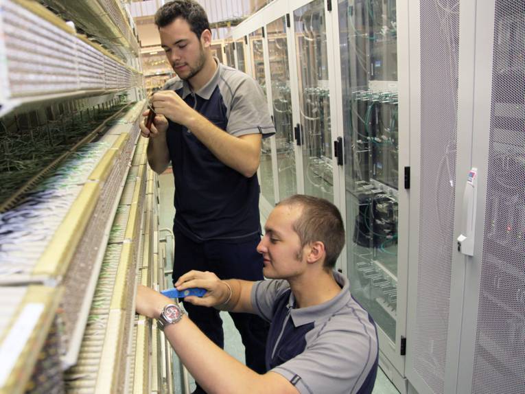 Zwei Auszubildende arbeiten an Kabeln in einem Serverraum