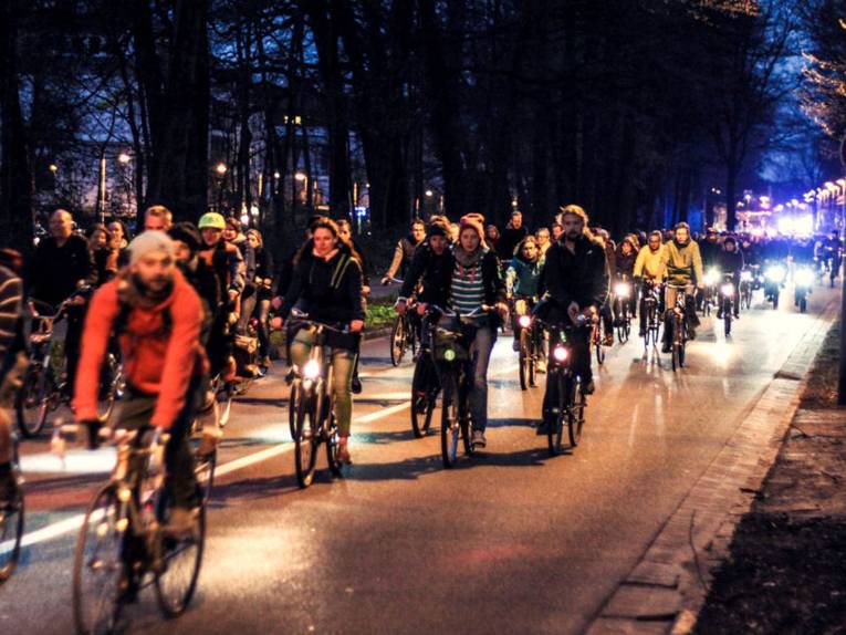 Viele Radfahrer auf einer Straße in der Nacht.