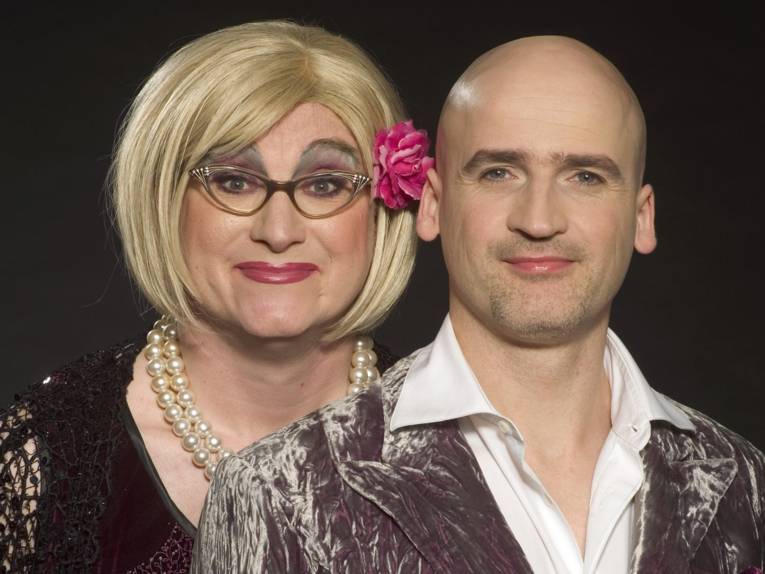 "Frau" und Mann in glitzernden Kostümen. 