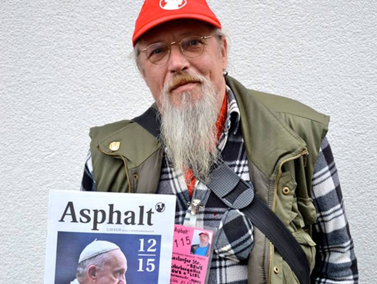 Ein Mann mit Bart und Baseballcap hält ein Magazin in der Hand.