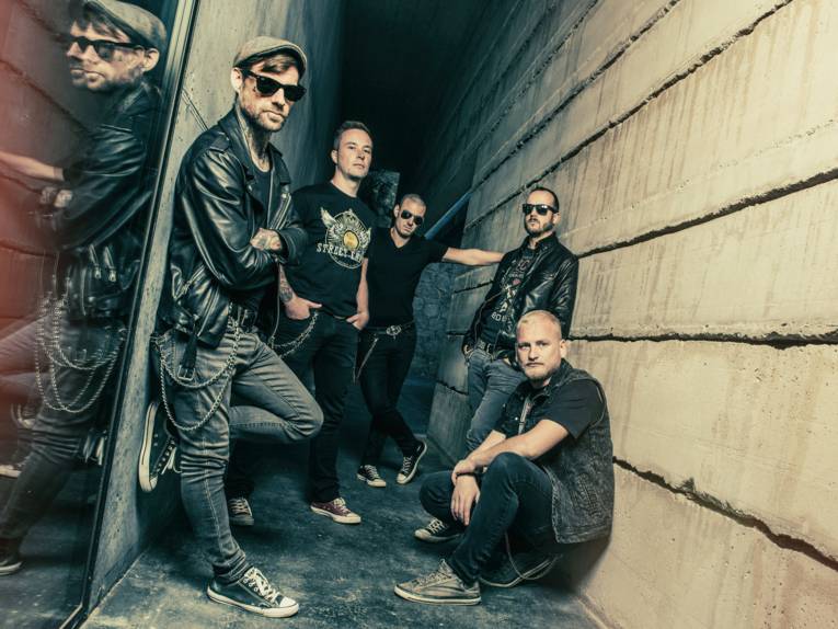 Fünf Männer lehnen und hocken an Wänden.