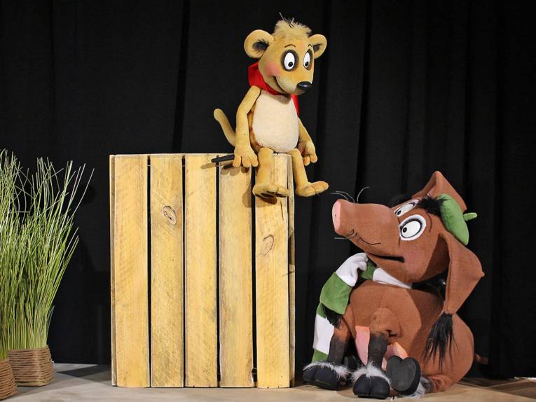 Zwei plüschige Puppen in Tiergestalt auf einer Bühne