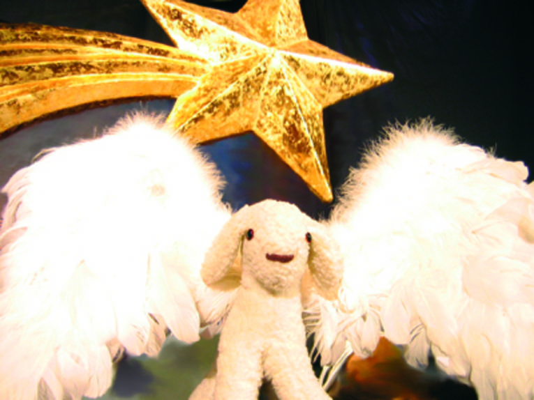 Eine Schafspuppe mit Flügeln unter einem goldenen Weihnachtsstern