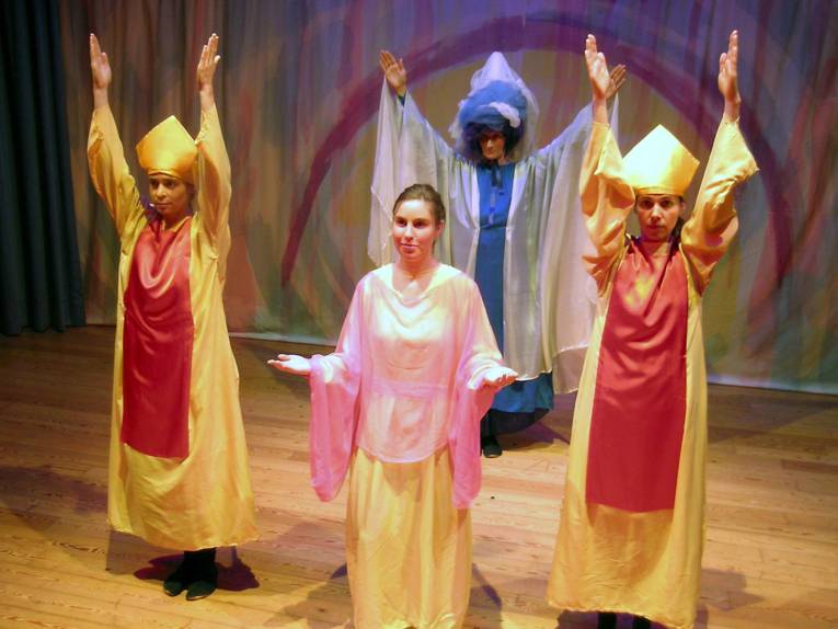 Vier Personen in langen Gewändern auf einer Bühne