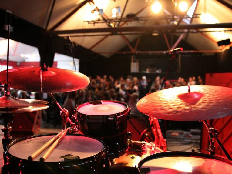 Foto von einem Schlagzeug. Im Hintergrund sieht man das Publikum. 