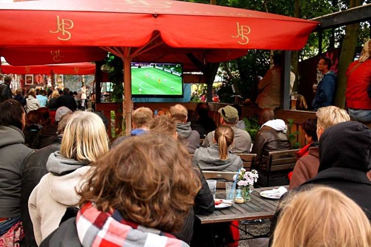 Leute schauen im Biergarten Fußball.