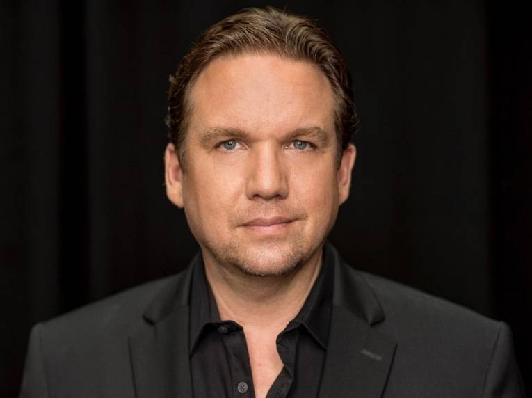 Porträt eines Mannes mit kurzem Haar und Dreitagebart in Hemd und Sakko