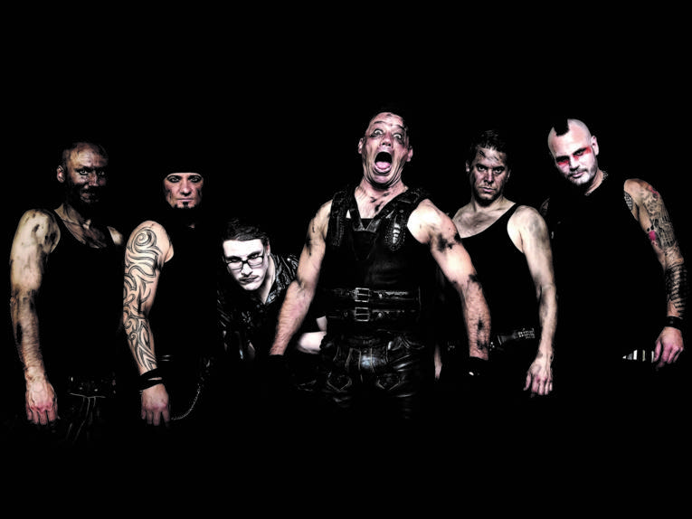 Sechs Männer mit Tattoos und schwarzer Kleidung schauen grimmig in die Kamera. Der Mann in der Mitte schreit.