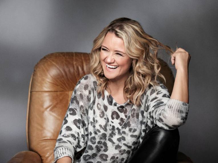 Eine Frau mit langen, blonden Haaren auf einem Ledersessel