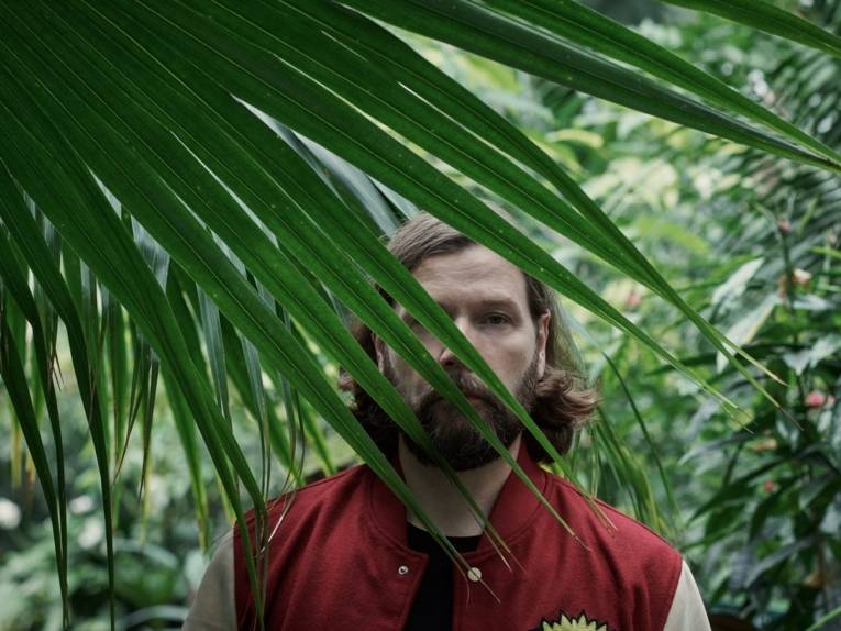 Mann hinter einem Palmenwedel