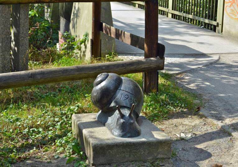 Skultpur einer Schnecke vor einer Brücke