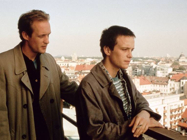 Zwei Männer auf einer Aussichtsterrasse mit Blick über eine Stadt.