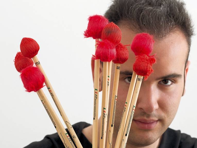 Mann mit Stöckern mit roten Wollspitzen