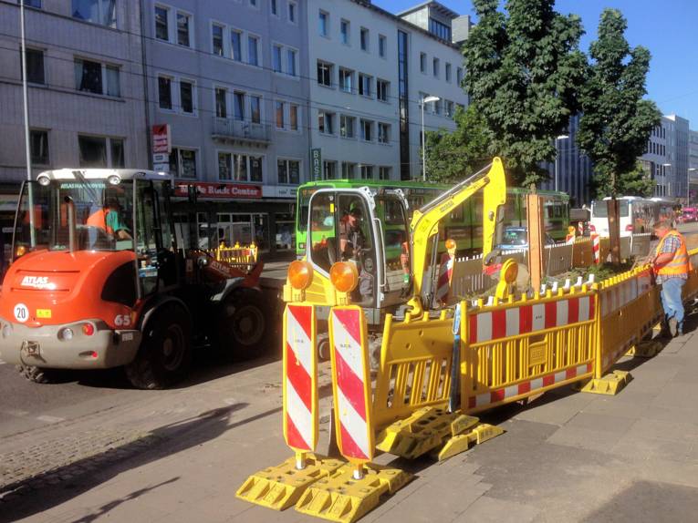 Baustelle mit Baustellenfahrzeugen mit Stadtbahn im Hintergrund