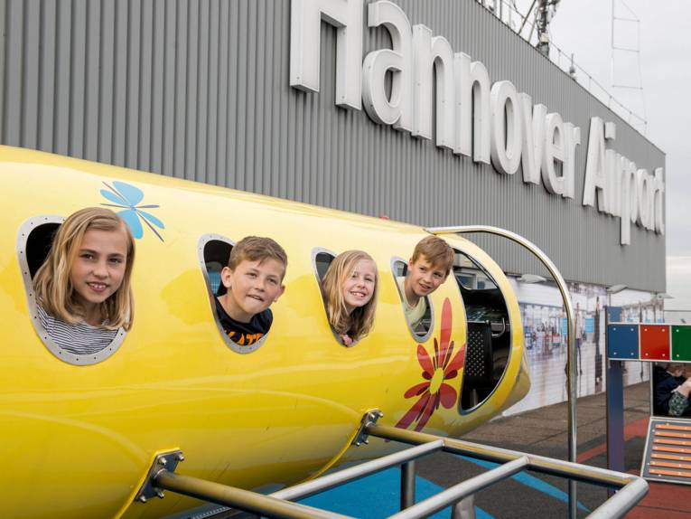 Kinder stecken ihre Köpfe aus kleinen runden Fenstern.