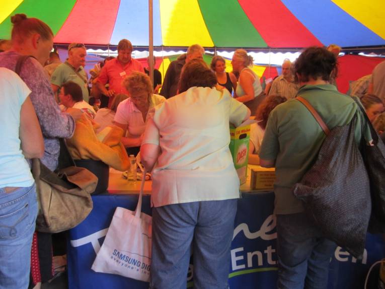 Menschen tauschen im bunten Tauschzelt verschiedene Dinge.