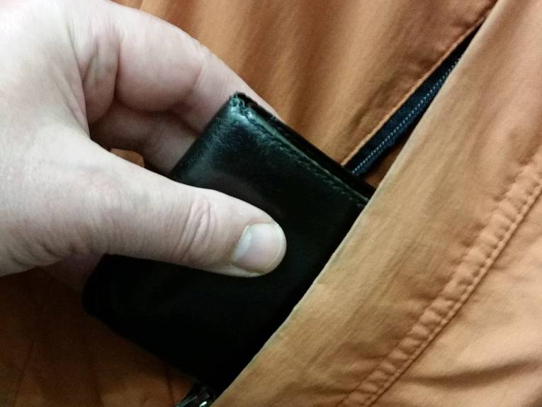 Hand zieht Geldbörse aus Jackentasche.
