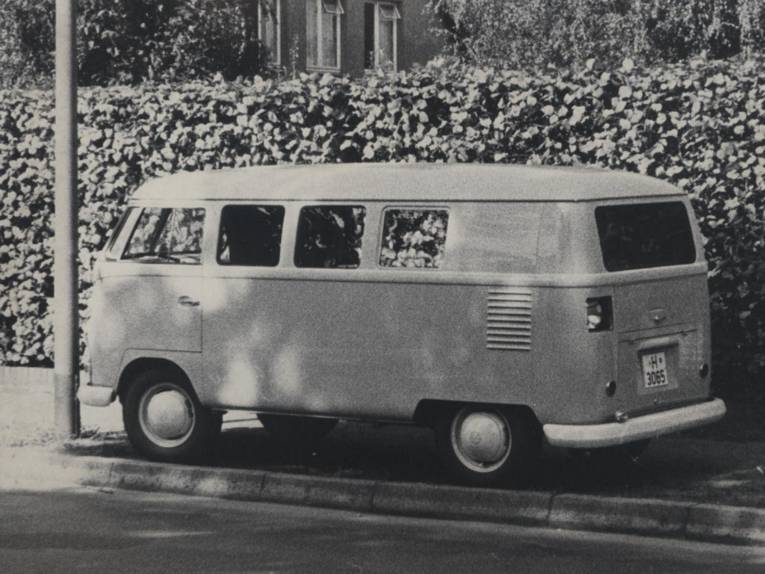VW Bulli Oldtimer am Straßenrand. Historische Schwarz-Weiß-Aufnahme.