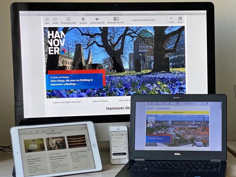 Es sind mehrere technische Geräte zu sehen: Ein Desktop-Computer, ein Smartphone, ein Handy und ein Laptop