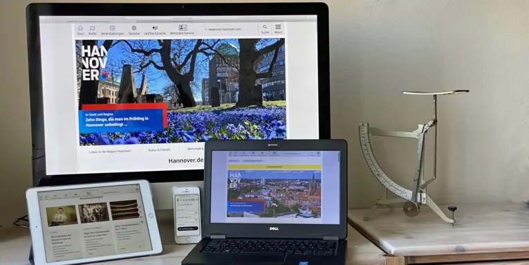 Es sind mehrere technische Geräte zu sehen: Ein Desktop-Computer, ein Smartphone, ein Handy und ein Laptop