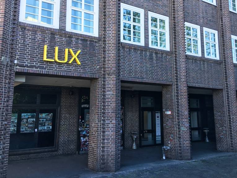 An einer Backsteinfassade steht in gelben Buchstaben "Lux".