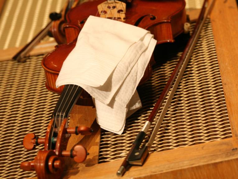 A violin (partly covered with a white cloth) and two bows.