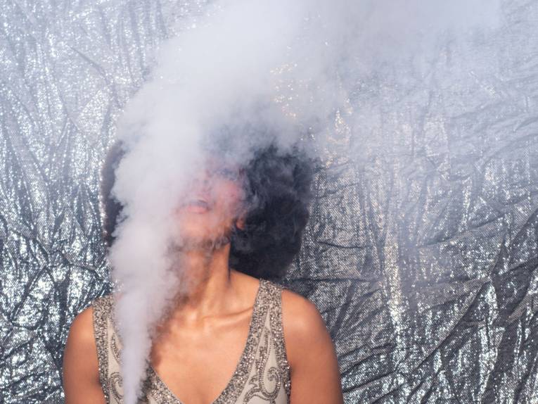 Gesicht einer Frau, fast komplett verdeckt von einer Rauchschwade