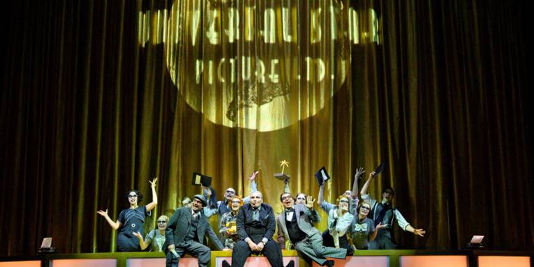 Bühnenszene: Eine Gruppe von Personen, die am Bühnenrand Grimassen schneiden