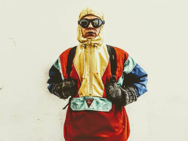 Winterlich gekleideter Mann mit Skibrille und dicken Handschuhen