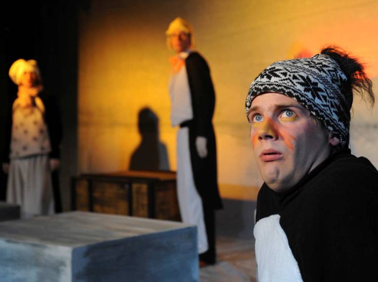 Drei als Pinguine kostümierte Schauspieler stehen versetzt auf der Bühne.