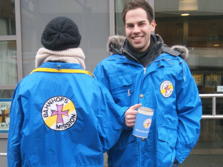 Zwei junge Leute in Jacken der Bahnhofsmission