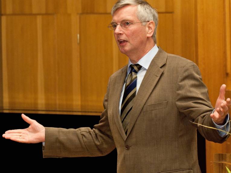 Ein Mann im Anzug und mit ausgebreiteten Armen