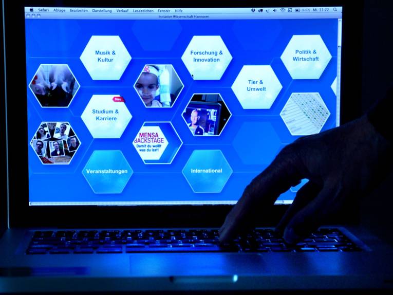 Aufgeklappter Laptop-Computer mit Hand.