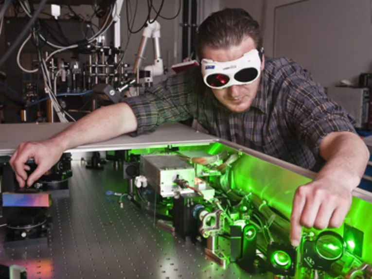 Ein Mann mit Schutzbrille führt ein physikalisches Experiment durch.