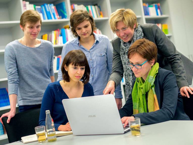 Fünf Frauen schauen auf einen Laptop.