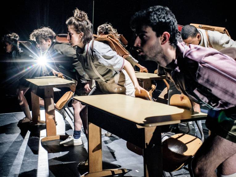 Menschen stehen vor Schulbänken