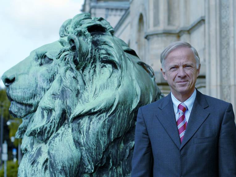 Ein Mann steht neben einen Löwen-Statue.
