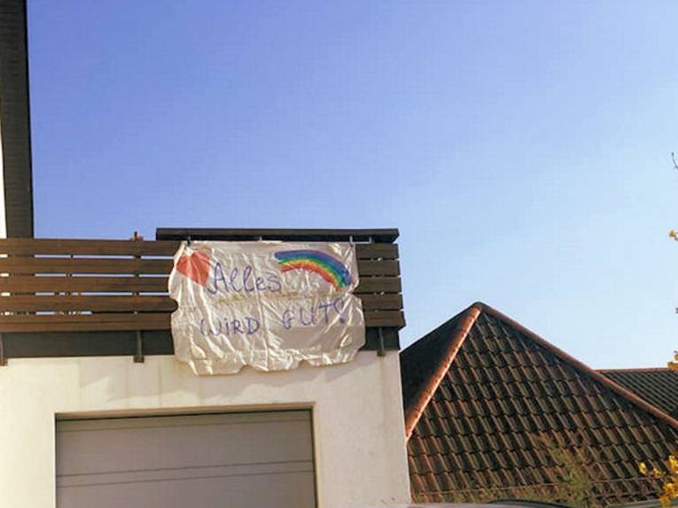 Fahne mit der Aufschrift "Alles wird gut" an Hauswand befestigt.