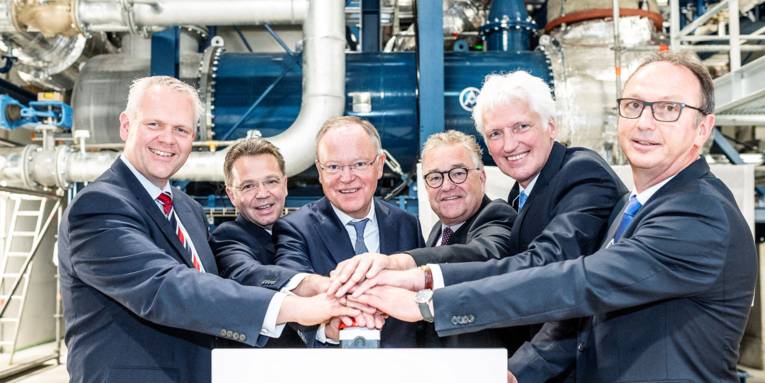 Sechs Männer drücken auf einen roten Knopf