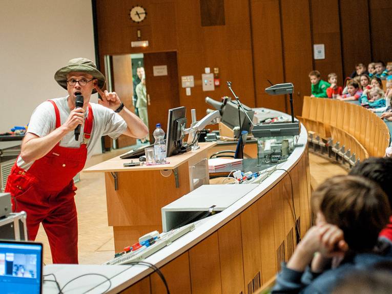 Mann in roter Latzhose in Hörsaal