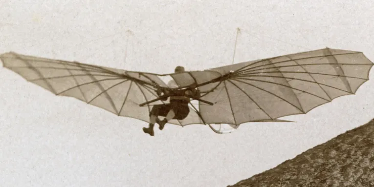 Mensch in Flugapparat, historische schwarz-weiß Aufnahme.
