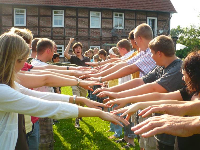 Junge Menschen stehen Spalier, im Hintergrund ist ein Mann zu sehen, der den Arm in die Höhe reckt.