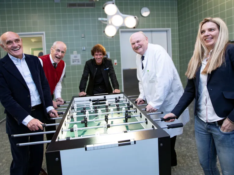 Vier Männer und eine Frau an einem Tischfußballtisch