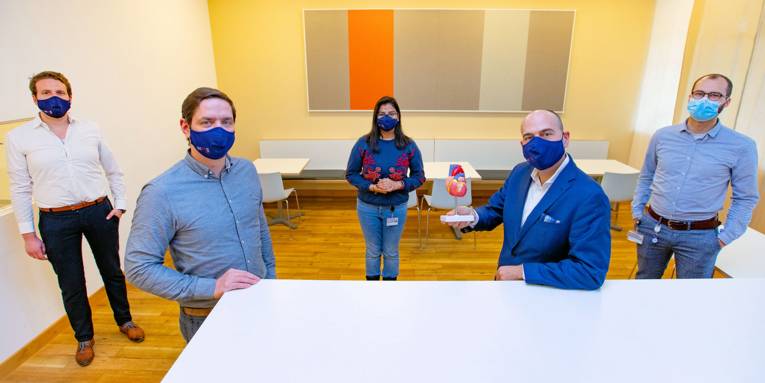 Menschengruppe, einer hält ein Modell eines Herzes in der Hand